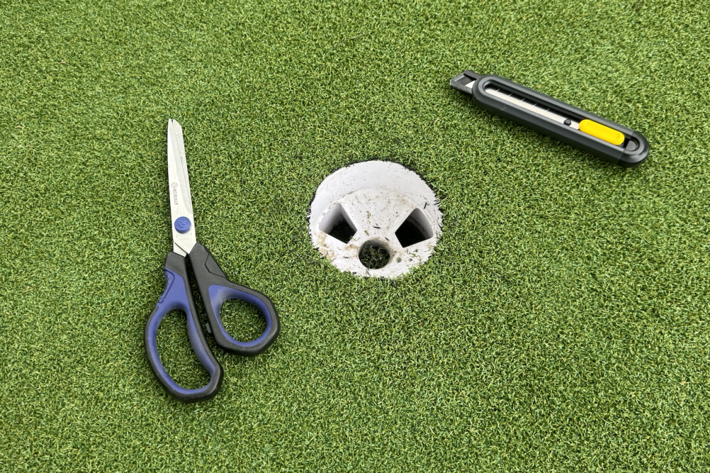 Cut a hole for the cup in the putting turf using a box cutter